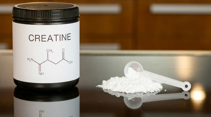 een pot creatine naast een schepje op een tafel