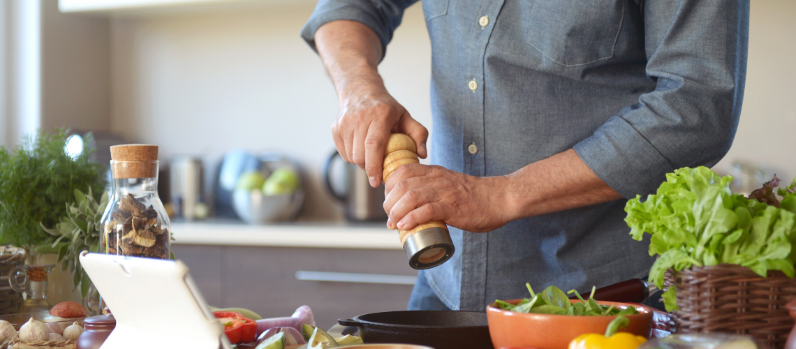 Man is in de keuken een gezonde maaltijd aan het klaarmaken - Bodystore.nl